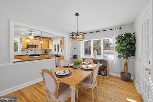 dining space with an inviting chandelier, sink, and light hardwood / wood-style flooring