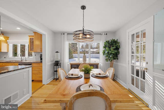 dining room featuring light wood-type flooring, sink, and an inviting chandelier