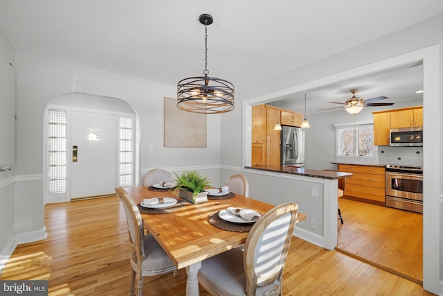 dining area featuring light hardwood / wood-style flooring and ceiling fan with notable chandelier