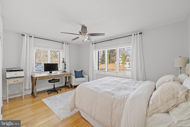 bedroom featuring multiple windows, hardwood / wood-style flooring, and ceiling fan