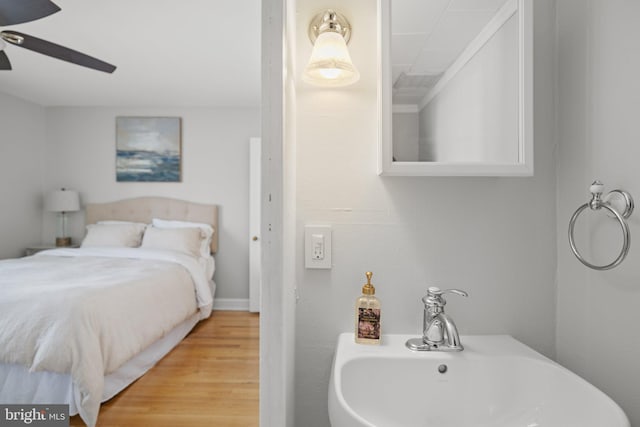 bedroom with hardwood / wood-style flooring, ceiling fan, and sink