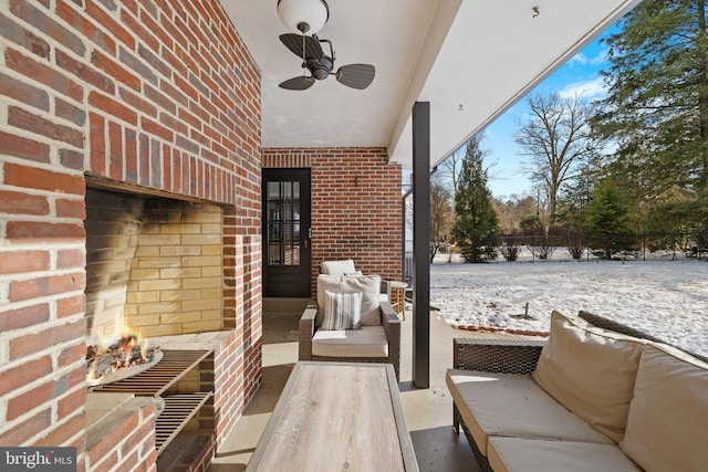 snow covered patio with ceiling fan and an outdoor living space