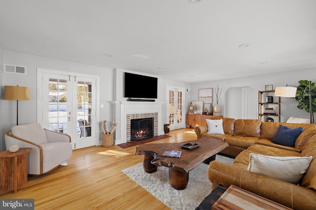 living room with a fireplace, french doors, and light hardwood / wood-style flooring