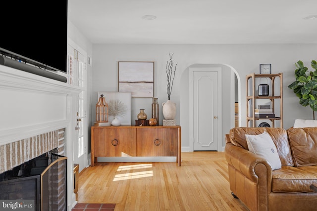 living room featuring light hardwood / wood-style flooring and a brick fireplace