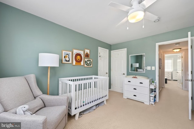 carpeted bedroom featuring a closet, a nursery area, and ceiling fan