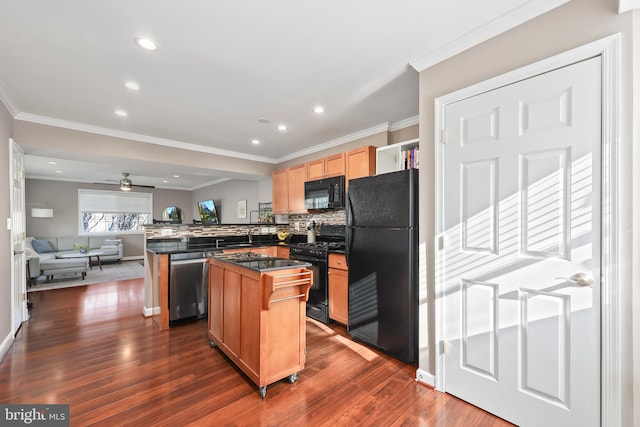 kitchen featuring dark wood-type flooring, a kitchen bar, a center island, and black appliances