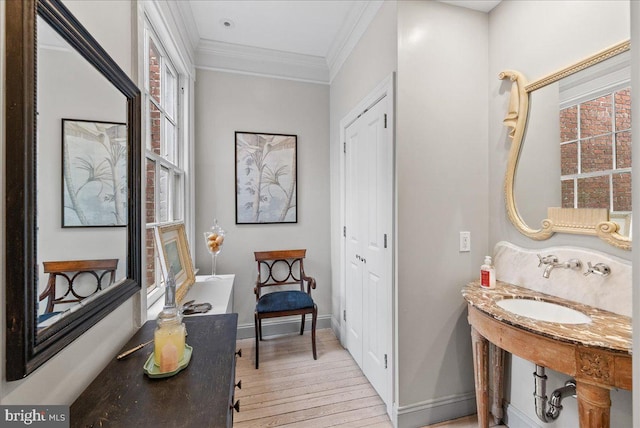 bathroom with hardwood / wood-style floors, crown molding, and sink