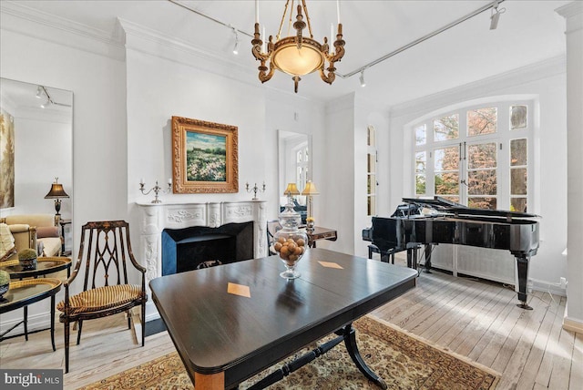 dining space featuring rail lighting, light hardwood / wood-style floors, ceiling fan with notable chandelier, and ornamental molding