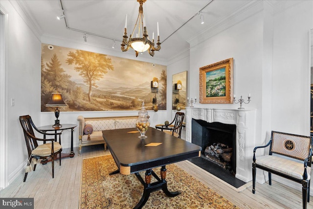 sitting room featuring crown molding, light wood-type flooring, rail lighting, and an inviting chandelier