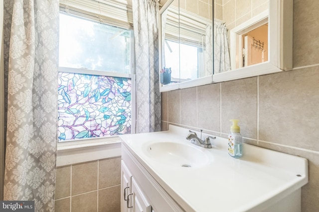 bathroom featuring vanity, plenty of natural light, and tile walls