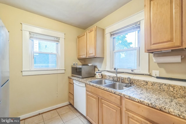 kitchen featuring dishwasher, sink, light tile patterned floors, and light brown cabinetry