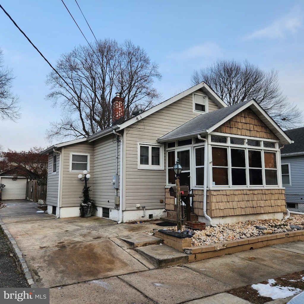 back of house with a sunroom, a garage, and an outdoor structure