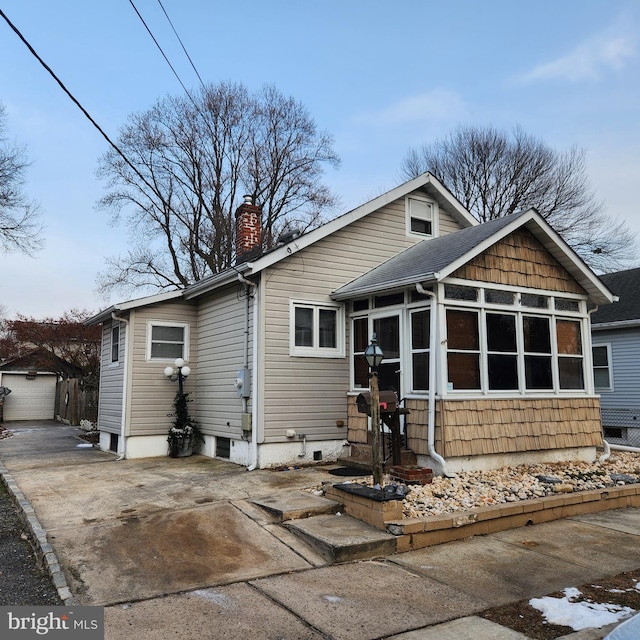 back of house with a sunroom, a garage, and an outdoor structure