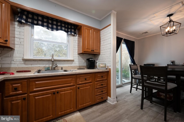 kitchen with sink, decorative light fixtures, an inviting chandelier, light hardwood / wood-style floors, and decorative backsplash