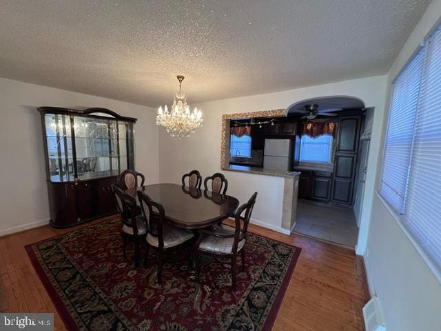 dining space featuring a textured ceiling, hardwood / wood-style floors, and ceiling fan with notable chandelier