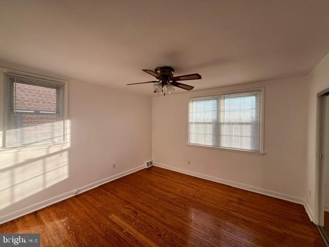 empty room with ceiling fan and dark hardwood / wood-style flooring