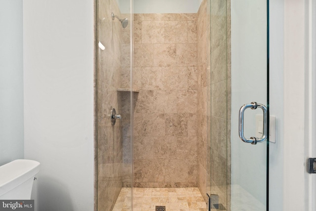 bathroom with a shower with shower door and toilet