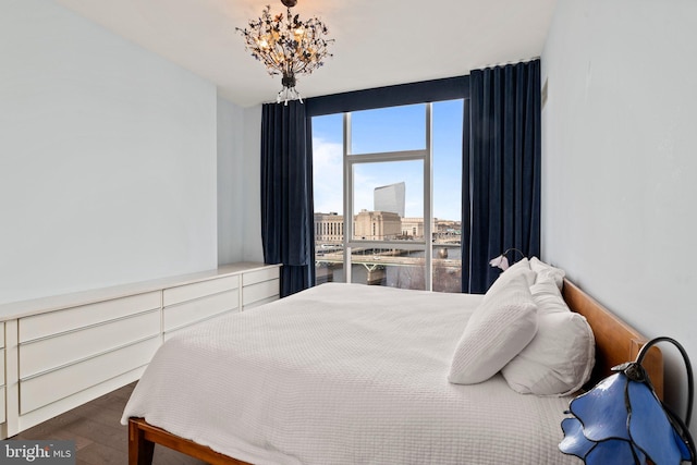 bedroom featuring expansive windows, a water view, dark wood-type flooring, and an inviting chandelier