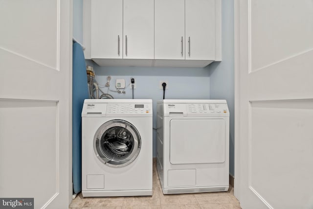 laundry area with cabinets, light tile patterned floors, and washing machine and clothes dryer