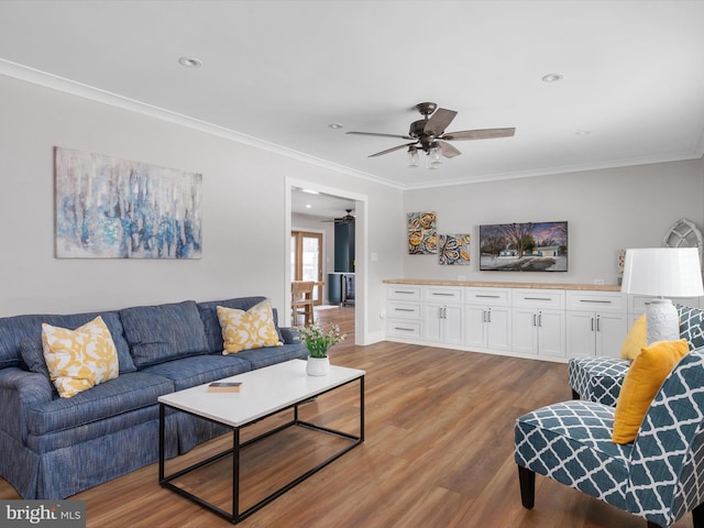 living room featuring ceiling fan, hardwood / wood-style flooring, and ornamental molding