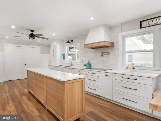 kitchen featuring black electric cooktop, white cabinetry, a kitchen island, and custom exhaust hood