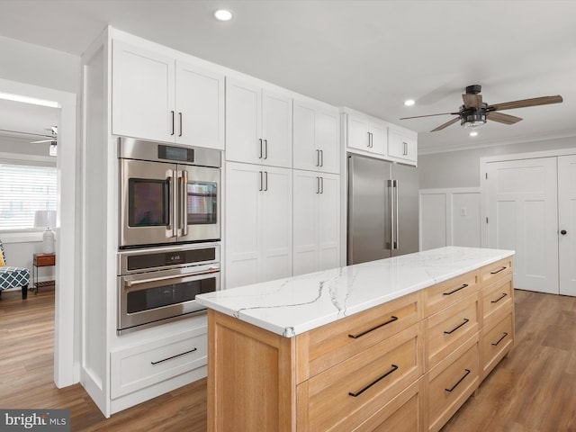 kitchen with white cabinets, double wall oven, hardwood / wood-style flooring, light brown cabinetry, and high end fridge