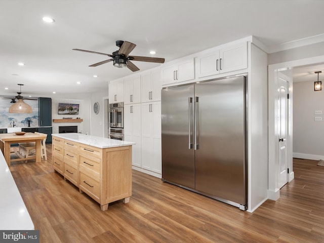 kitchen featuring white cabinets, hanging light fixtures, and stainless steel built in refrigerator