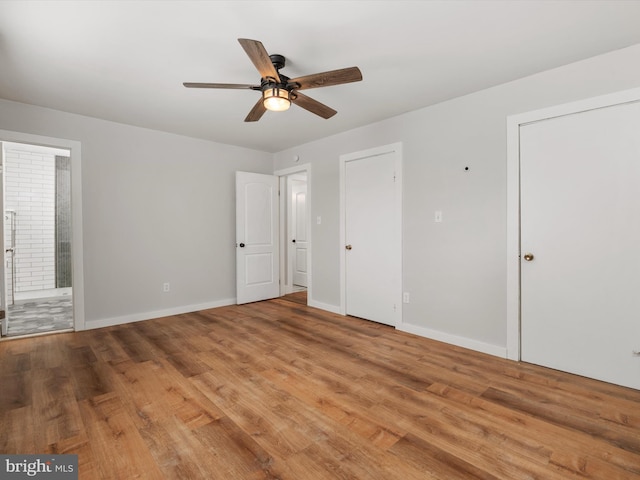 unfurnished bedroom featuring ensuite bath, ceiling fan, and hardwood / wood-style flooring