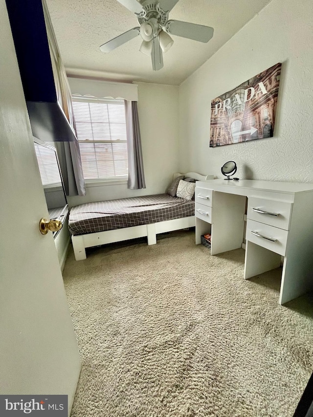 bedroom featuring ceiling fan, light carpet, and a textured ceiling