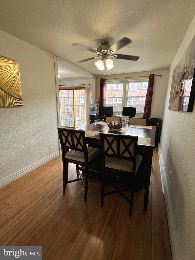 dining area featuring ceiling fan, wood-type flooring, and a textured ceiling