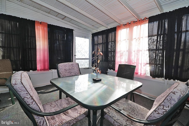 carpeted dining space with vaulted ceiling