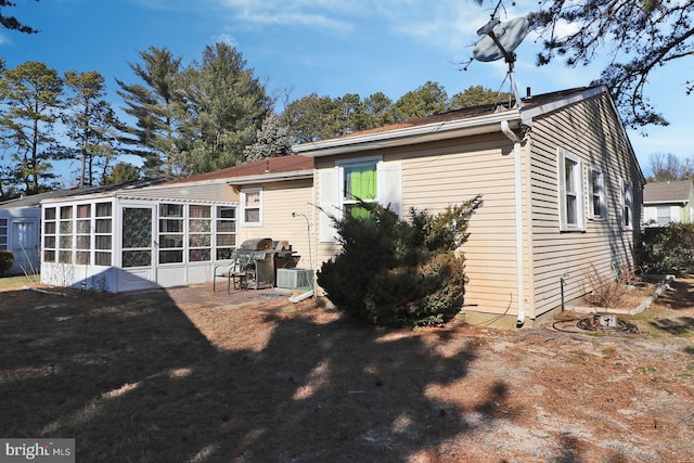 rear view of house featuring central air condition unit and a sunroom