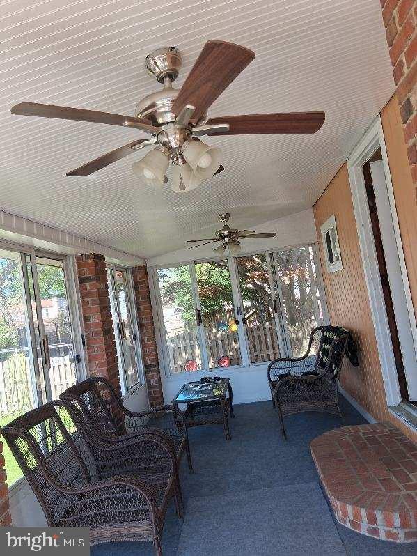 sunroom with ceiling fan and carpet