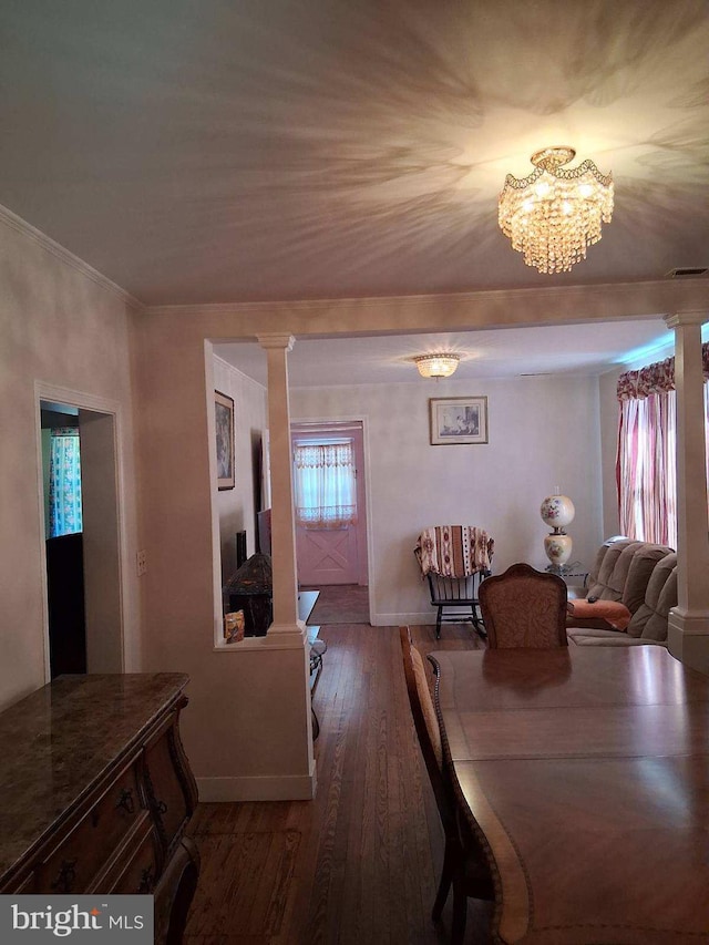 dining space featuring an inviting chandelier, ornate columns, wood finished floors, and baseboards