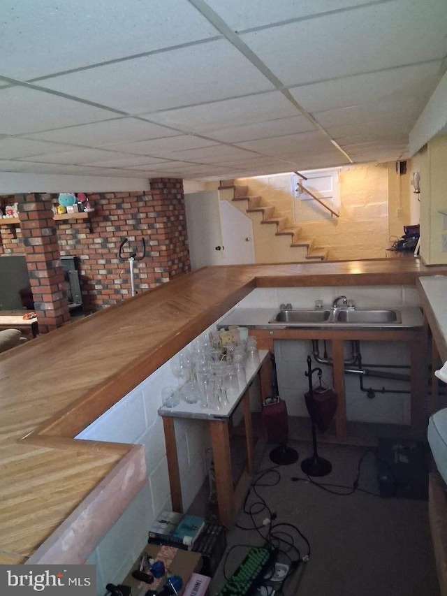 bar featuring stairway, a sink, and a drop ceiling