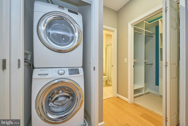 clothes washing area with stacked washer and dryer and light hardwood / wood-style flooring