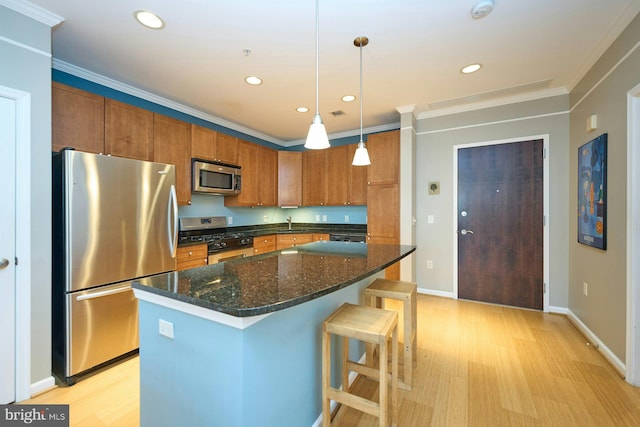 kitchen with a center island, dark stone countertops, crown molding, decorative light fixtures, and appliances with stainless steel finishes