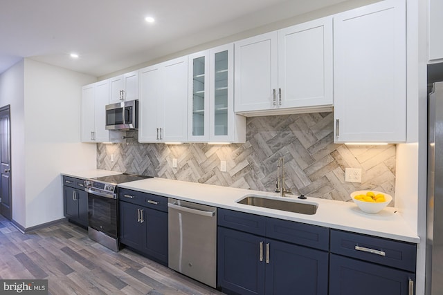 kitchen with appliances with stainless steel finishes, blue cabinets, dark wood-type flooring, sink, and white cabinets