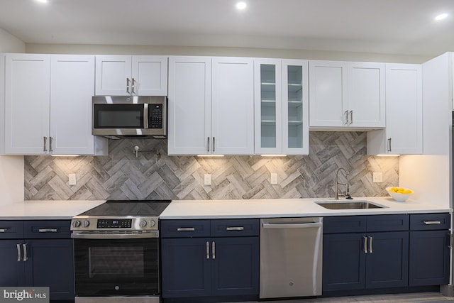 kitchen with decorative backsplash, stainless steel appliances, white cabinetry, and sink