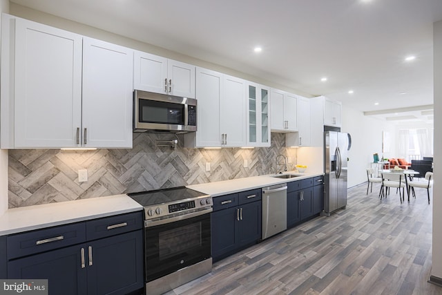 kitchen with backsplash, stainless steel appliances, sink, hardwood / wood-style flooring, and white cabinets