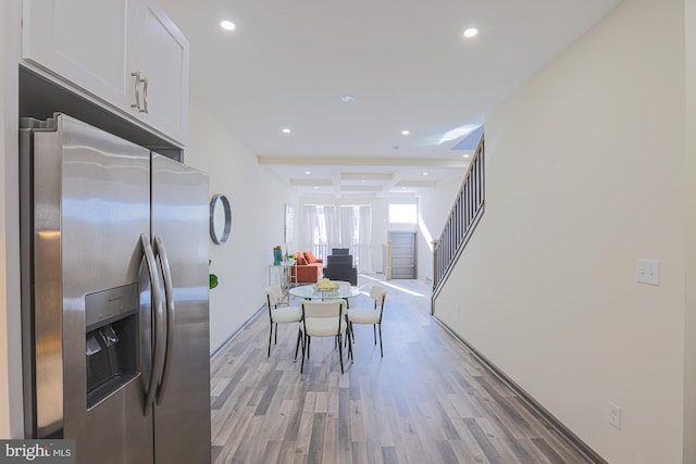 kitchen with white cabinetry, coffered ceiling, beamed ceiling, stainless steel fridge, and light hardwood / wood-style floors