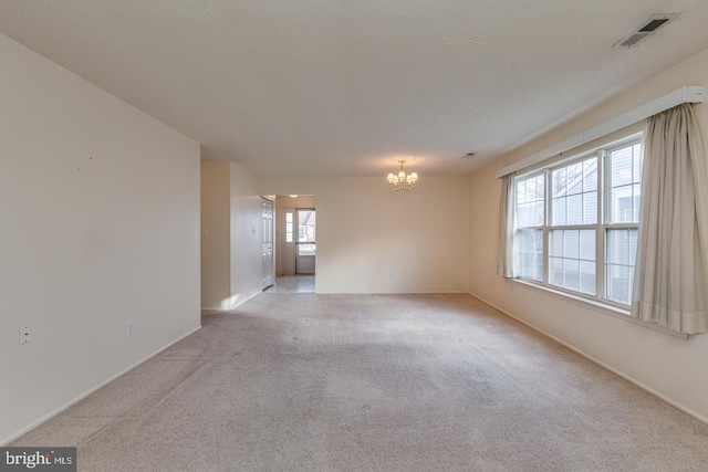 unfurnished room featuring light carpet, a healthy amount of sunlight, and a notable chandelier