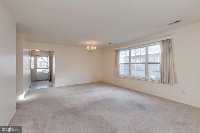 carpeted empty room with a notable chandelier