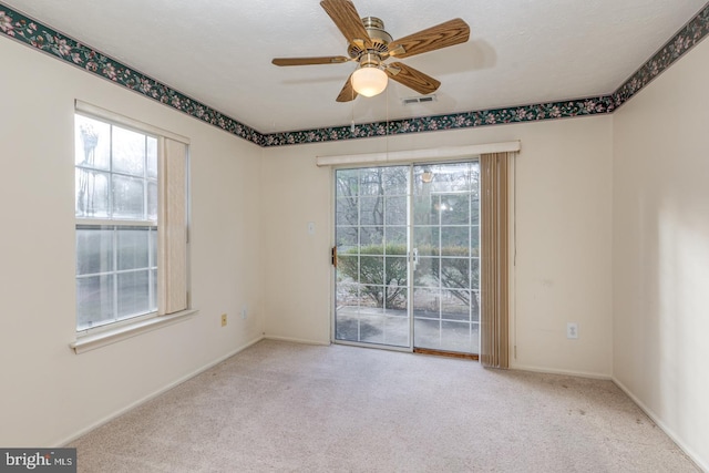 empty room featuring light carpet, a textured ceiling, ceiling fan, and a healthy amount of sunlight