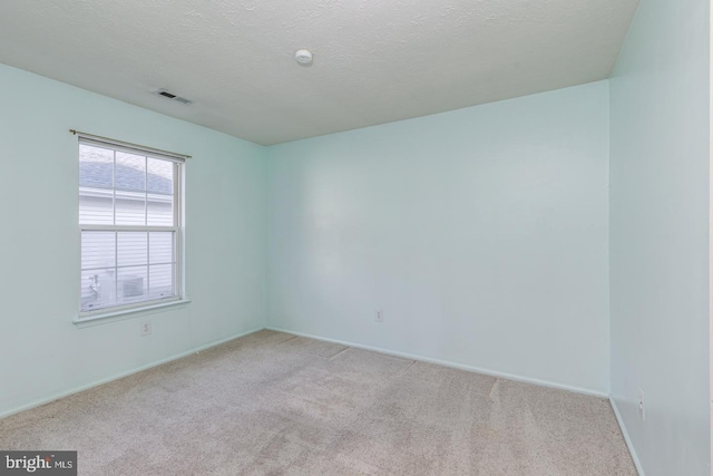 unfurnished room featuring a textured ceiling and light colored carpet