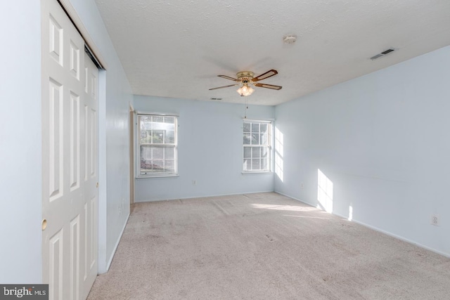 empty room with a textured ceiling, ceiling fan, and light carpet