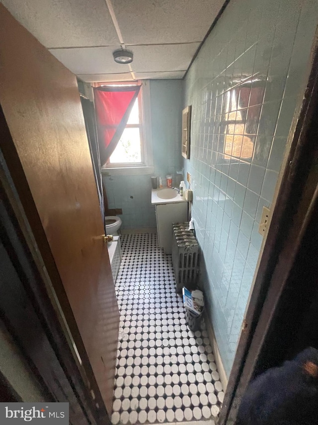 bathroom with radiator heating unit, vanity, toilet, and tile walls