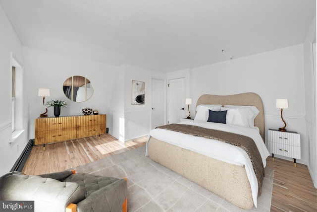 bedroom featuring baseboard heating and hardwood / wood-style floors