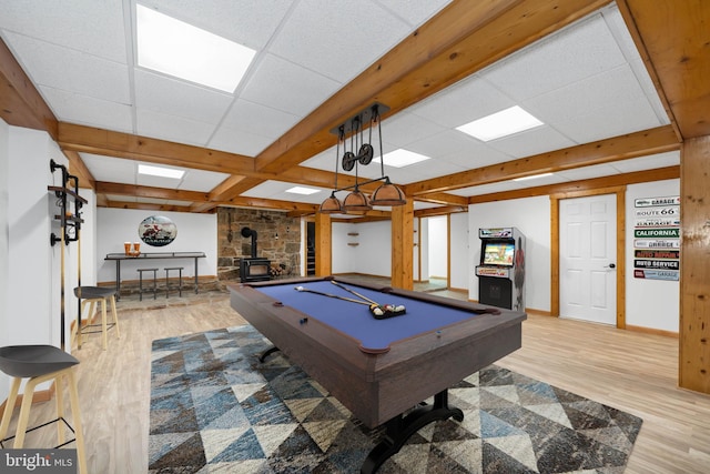 recreation room featuring a wood stove, a paneled ceiling, and light hardwood / wood-style flooring