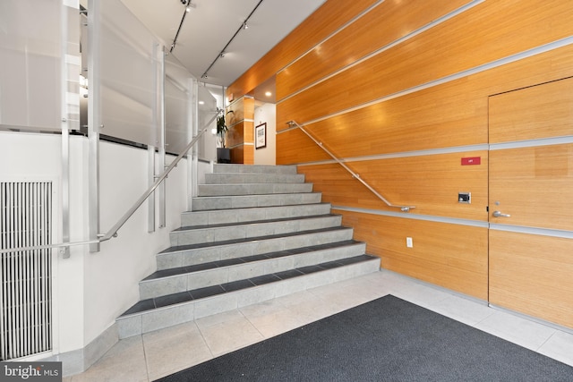 staircase with tile patterned floors and rail lighting